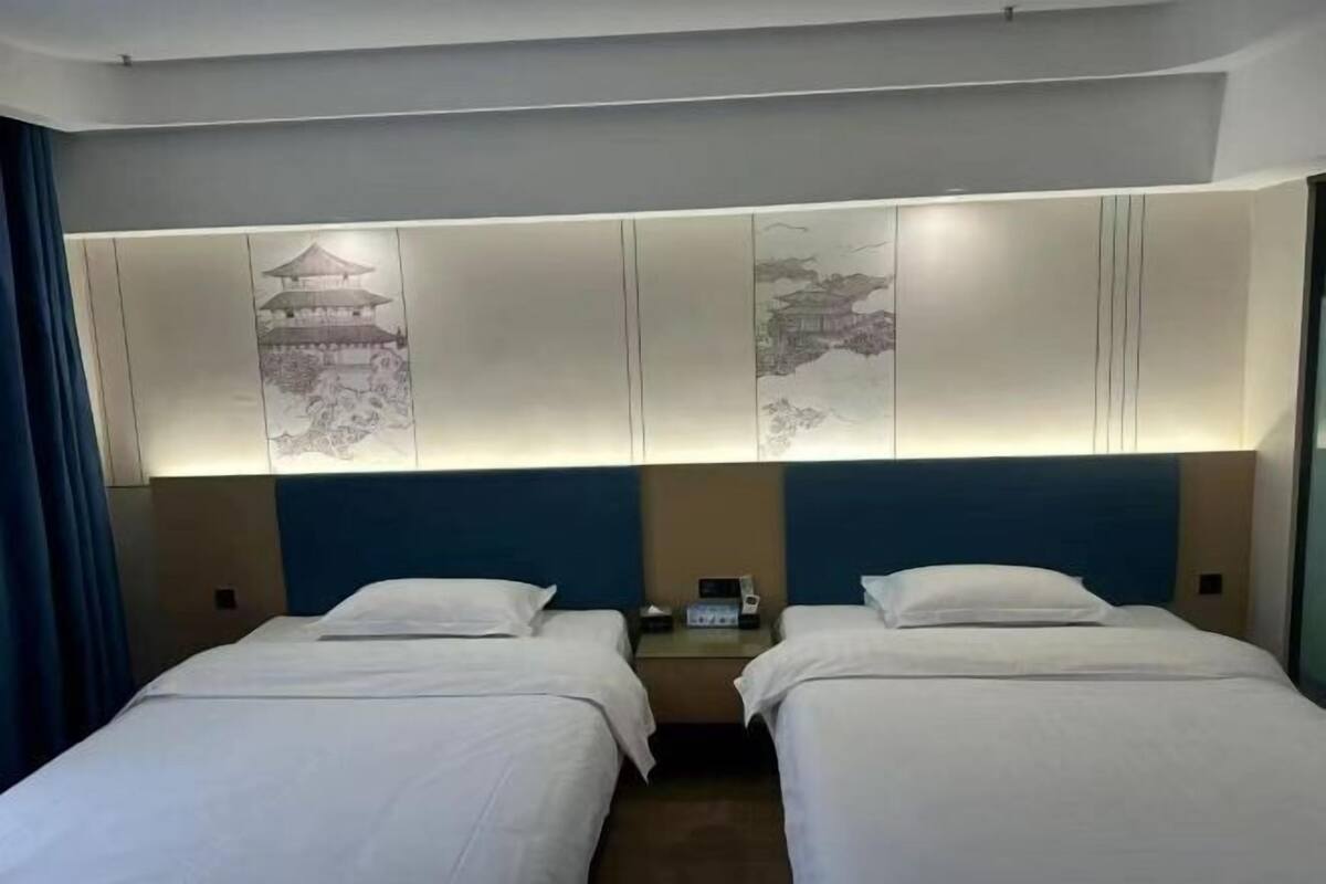 Une chambre d’hôtel avec deux lits, une tête de lit décorée, une table de chevet et un téléphone.