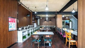 L’intérieur d’un restaurant avec des murs en bois, des tables, des chaises et des lampes suspendues.