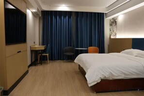 Een hotelkamer met een bed, bureau, stoel en gordijn.
