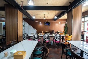 Un interior de restaurante con mesas, sillas y una pantalla de televisión.