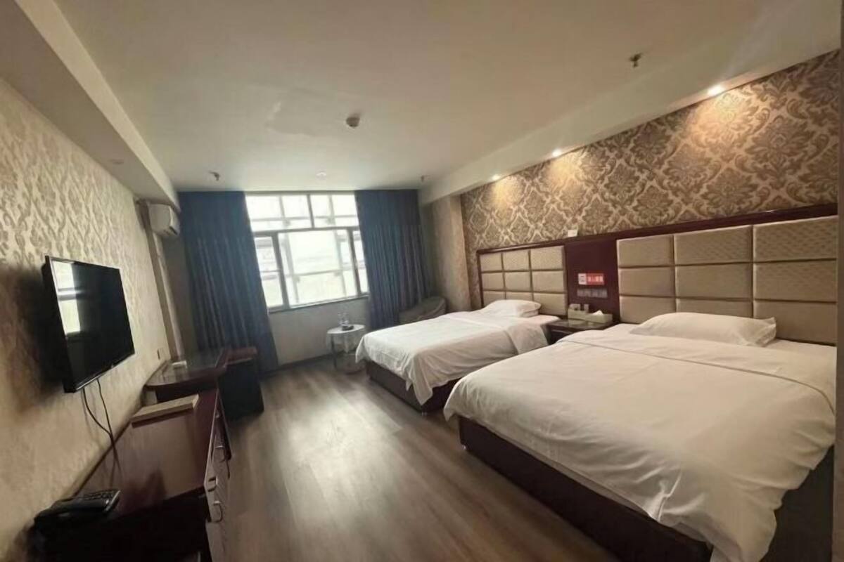 Une chambre d’hôtel avec deux lits, une télévision, un bureau et une fenêtre.