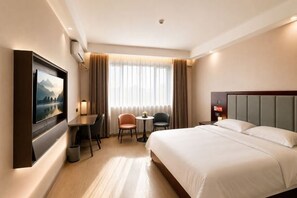 A hotel room with a bed, a desk, two chairs, a TV, and a window with curtains. - Jinse Sunshine Hotel (Baicheng)