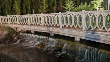 A bridge with a decorative railing over a flowing stream.