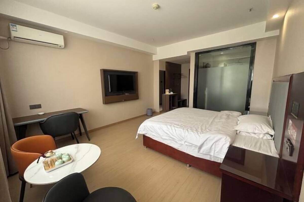 Une chambre d’hôtel équipée d’un lit, d’un bureau, d’une chaise, d’une télévision et d’une petite table sur laquelle se trouve un plateau avec de la nourriture.