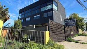 A modern building with multiple windows and a sign indicating it houses tourist offices. - Ocean view in Rukalafquen (Dichato)