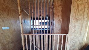 A wooden interior with a metal gate, a visible light fixture, and a glimpse of a vehicle through the gate. - Ocean view in Rukalafquen (Dichato)