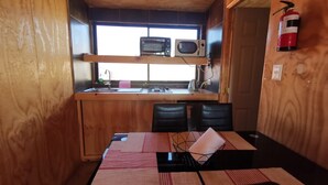 A compact kitchen with a microwave, toaster, and sink. There is a dining table with chairs and a fire extinguisher mounted on the wall. - Ocean view in Rukalafquen (Dichato)