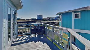 A wooden deck with a railing, leading to a building with a blue exterior. - Sunday Villas Sunday Funday by Silver Sands Vacation Rentals (Port Aransas)