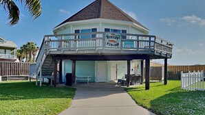 A two-story building with a balcony, a sign reading "Sunday Fun Day," and a covered outdoor seating area. - Sunday Villas Sunday Funday by Silver Sands Vacation Rentals (Port Aransas)