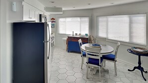 A compact kitchen with a refrigerator, a dining table with chairs, and a small island with a sink. - Sunday Villas Sunday Funday by Silver Sands Vacation Rentals (Port Aransas)