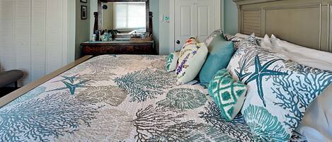 A bedroom with a bed, a dresser, a mirror, and a ceiling fan.