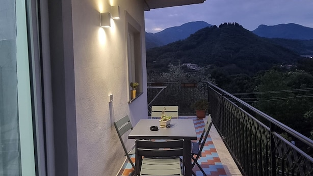 Un balcón con mesa y sillas, vistas a montañas y un piso con diseño.