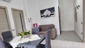 Una sala de estar moderna con una mesa de comedor, sillas, un sofá y un cuadro en la pared.