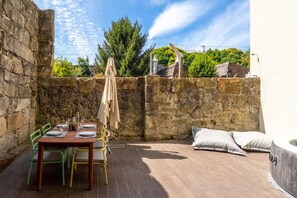 A patio with a table set for dining, a covered area, and a stone wall.