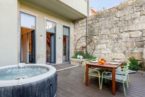 Ein Whirlpool, ein Gartentisch mit Stühlen und eine Steinmauer.