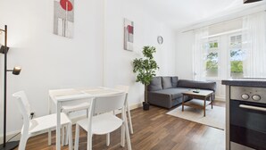 Una sala moderna con comedor, un sofá gris, una mesita y una planta en maceta.