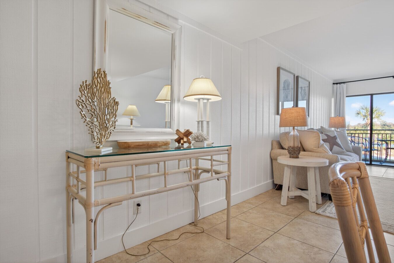 Una habitación con una mesa de centro de vidrio, un espejo grande y un rincón de estar con un sofá y sillones.