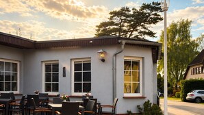 An outdoor seating area with tables and chairs, a signboard, and a lamp post. - Pension Vineta Rügen (Ostseebad Baabe)