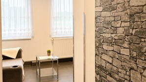 A room with a stone wall, a radiator, a small table with a plant, and a bed. - Pension Vineta Rügen (Ostseebad Baabe)