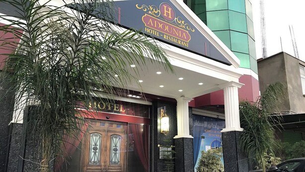 L’extérieur de l’hôtel Adounia se distingue par son imposante entrée, ses colonnes et un tapis rouge menant à la porte.