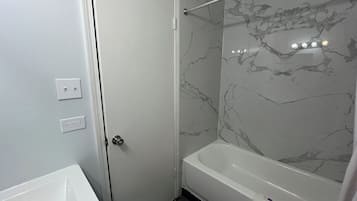 A bathroom with a white bathtub, a shower area, and a white sink.