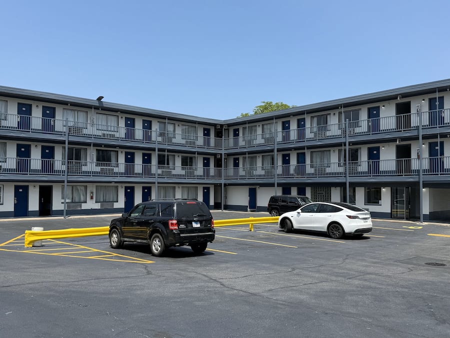 Un motel de varios pisos con estacionamiento.