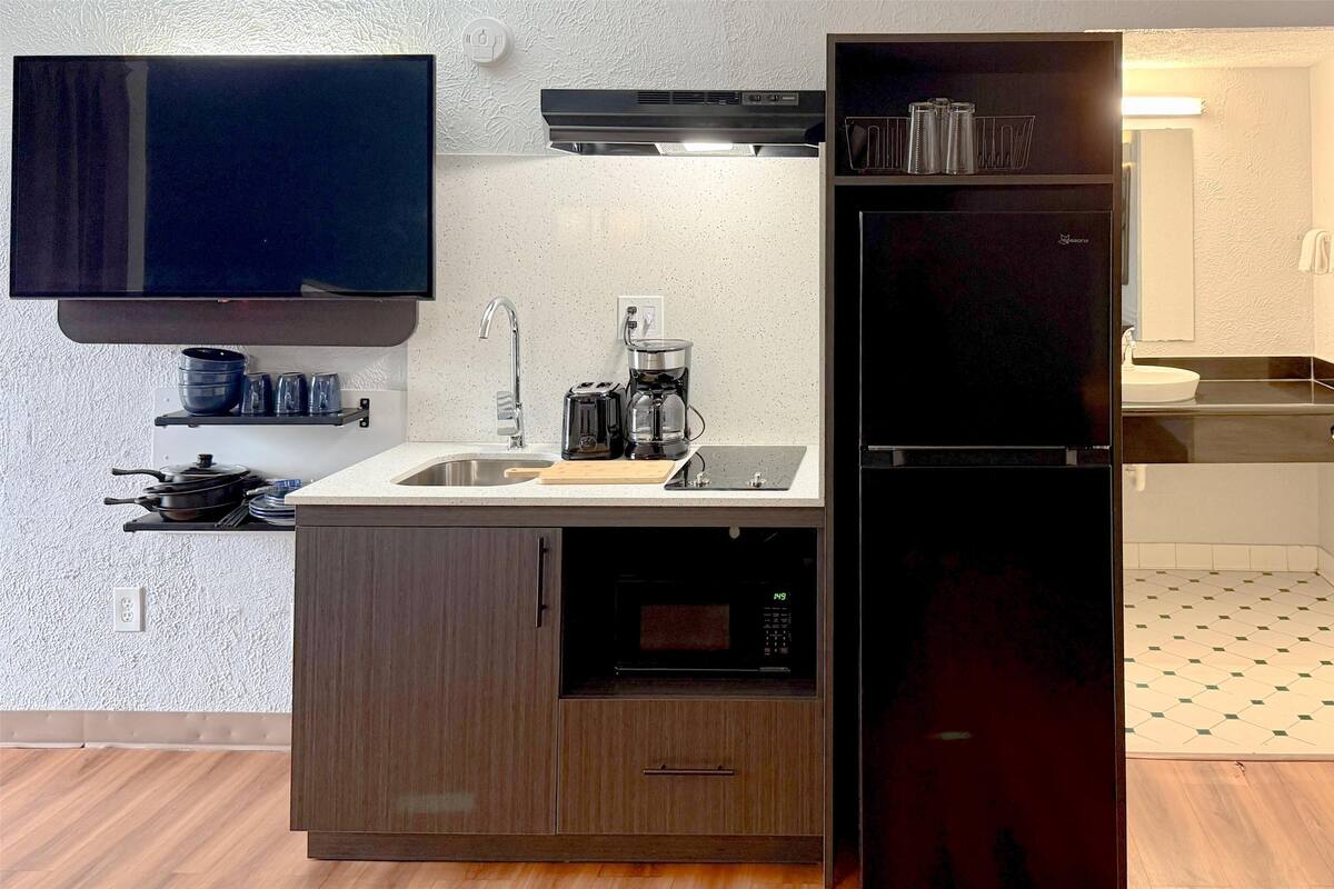 Ett kompakt kök med en inbyggd ugn, en kaffebryggare och ett kylskåp.