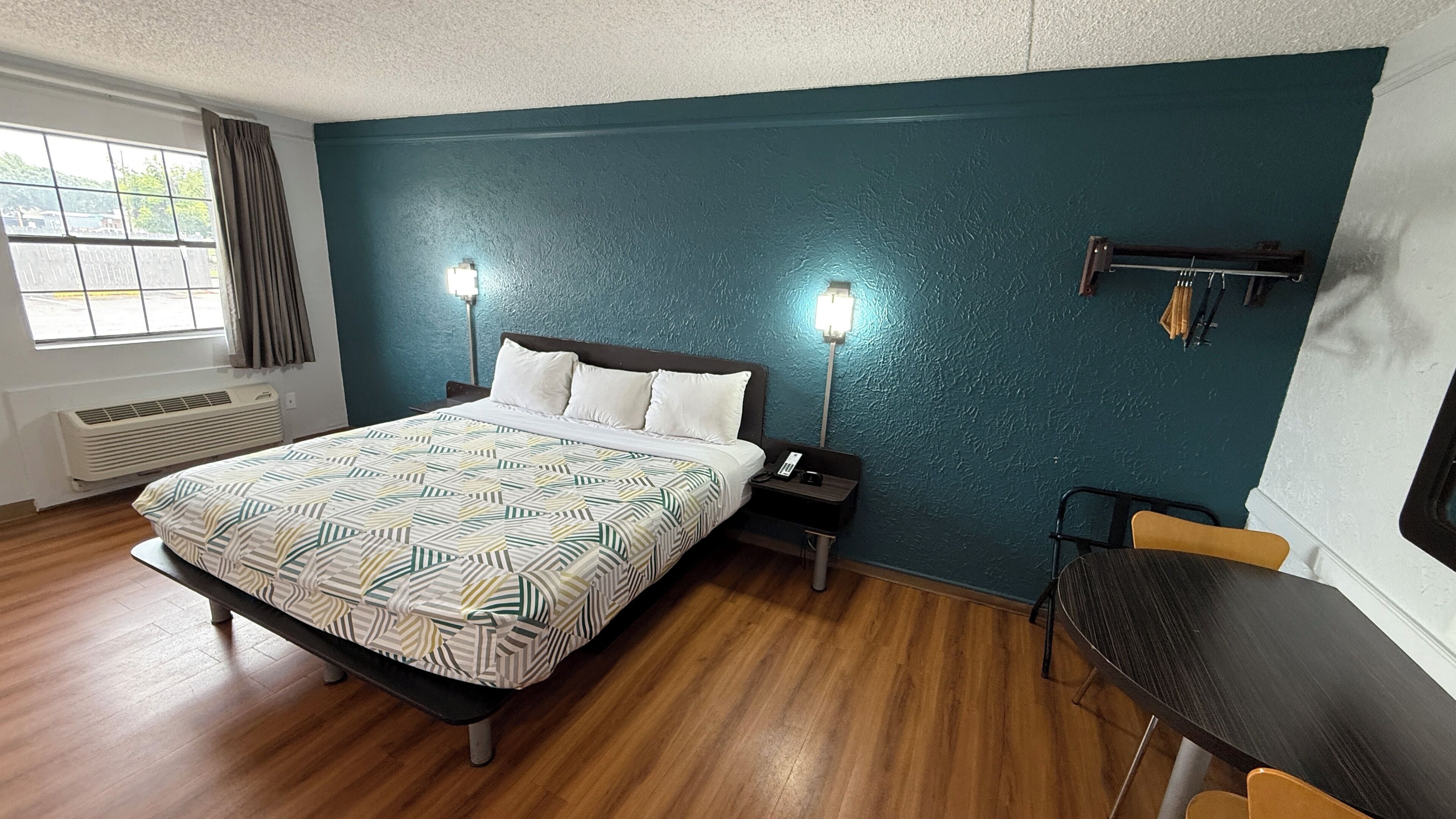 Habitació d'hotel amb un llit, taules de nit, escriptori i una cadira.