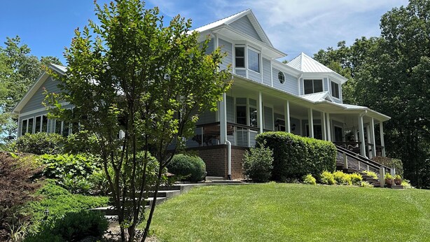 A large, two-story house with a covered front porch and a well-maintained lawn.
