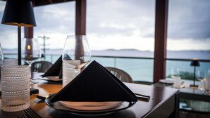 A dining table set with a black napkin, a clear glass, and a textured glass candle holder. - The Saint Resort (St. John)