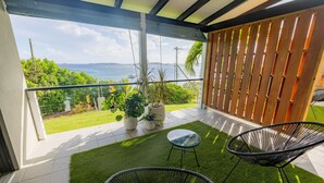 A balcony with a view of the sea, two black chairs, and a small table. - The Saint Resort (St. John)