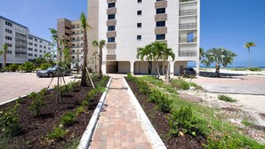 A multi-story hotel with a central courtyard, palm trees, and a view of the beach.