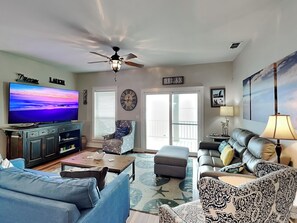 Relax in a comfortable living space with a flat-screen TV, ceiling fan, and large window.