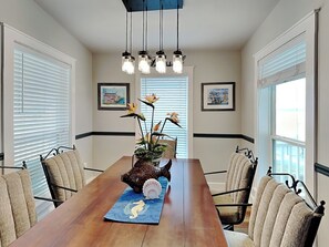 A dining room with a wooden table, chairs, hanging pendant lights, and framed artwork on the walls. - Casa Del Sol by Miss Kitty’s (Rockport)
