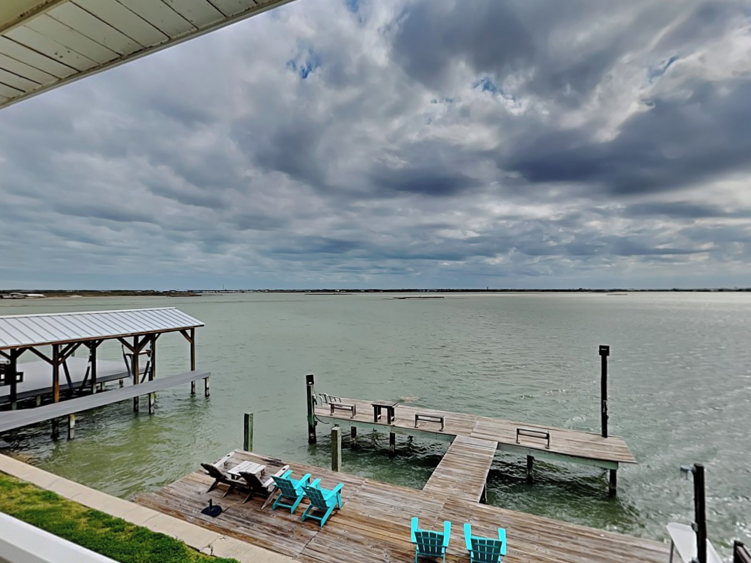 A dock extending into a calm body of water with a cloudy sky above.