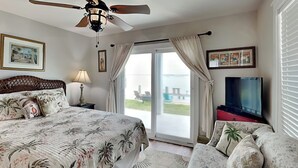 Camera da letto con un letto, una ventola a soffitto, una TV e vista all'esterno tramite una porta scorrevole in vetro.