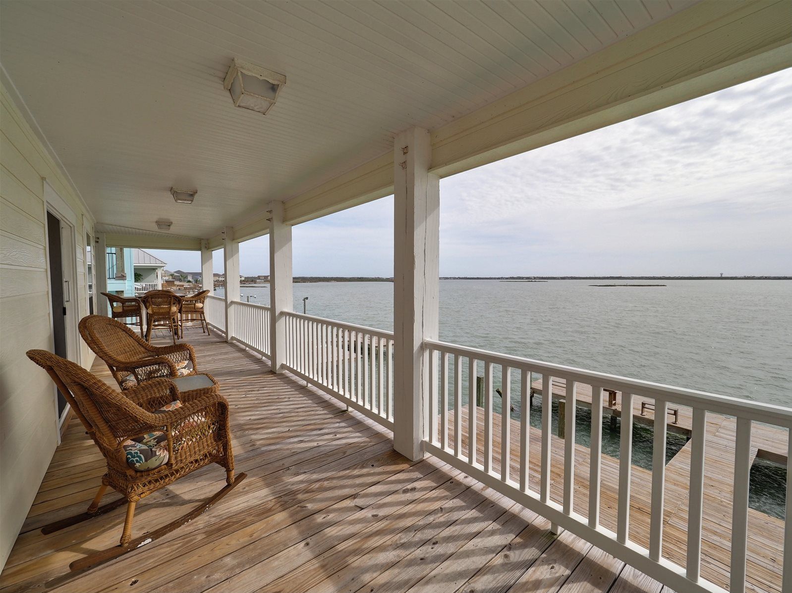 A wooden deck with wicker furniture and a view of the water.