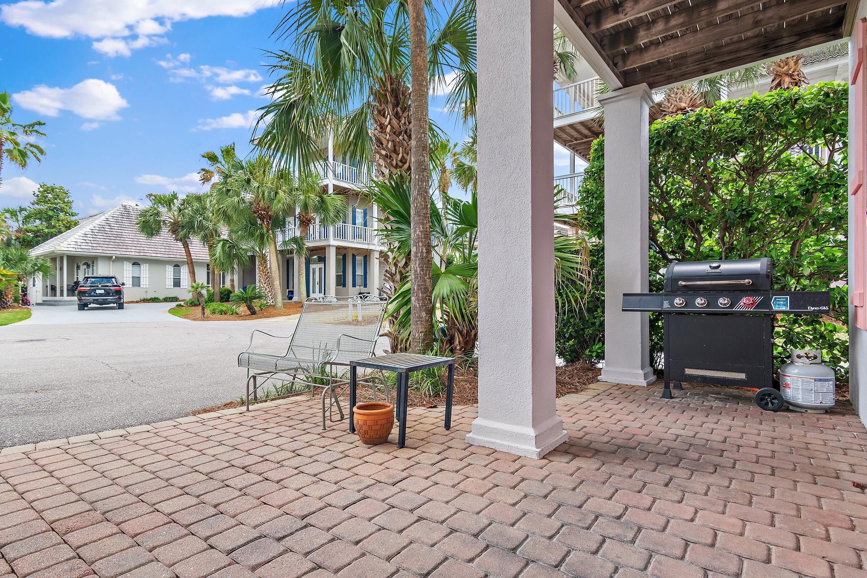 A covered outdoor area with a grill, a table with a planter, and a bench.