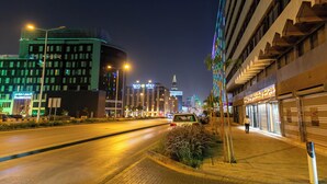 A modern hotel with a prominent sign, a well-lit street, and a pedestrian walkway. - Centrally Located Self Checkin Luxury  Apartment (Riyadh)