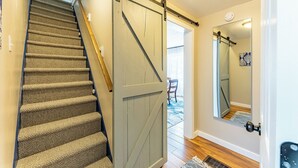 A staircase with a wooden handrail and carpeted steps leading to a room with a sliding barn-style door.