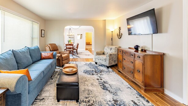 A living room with a sofa, ottoman, and a wooden cabinet.
