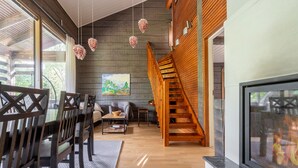 Un intérieur moderne avec un escalier en bois, un coin repas et une cheminée.