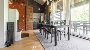 Une cuisine moderne agrémentée d’éléments en bois, un coin repas avec une grande table et des chaises, et de grandes fenêtres qui laissent entrer la lumière naturelle.