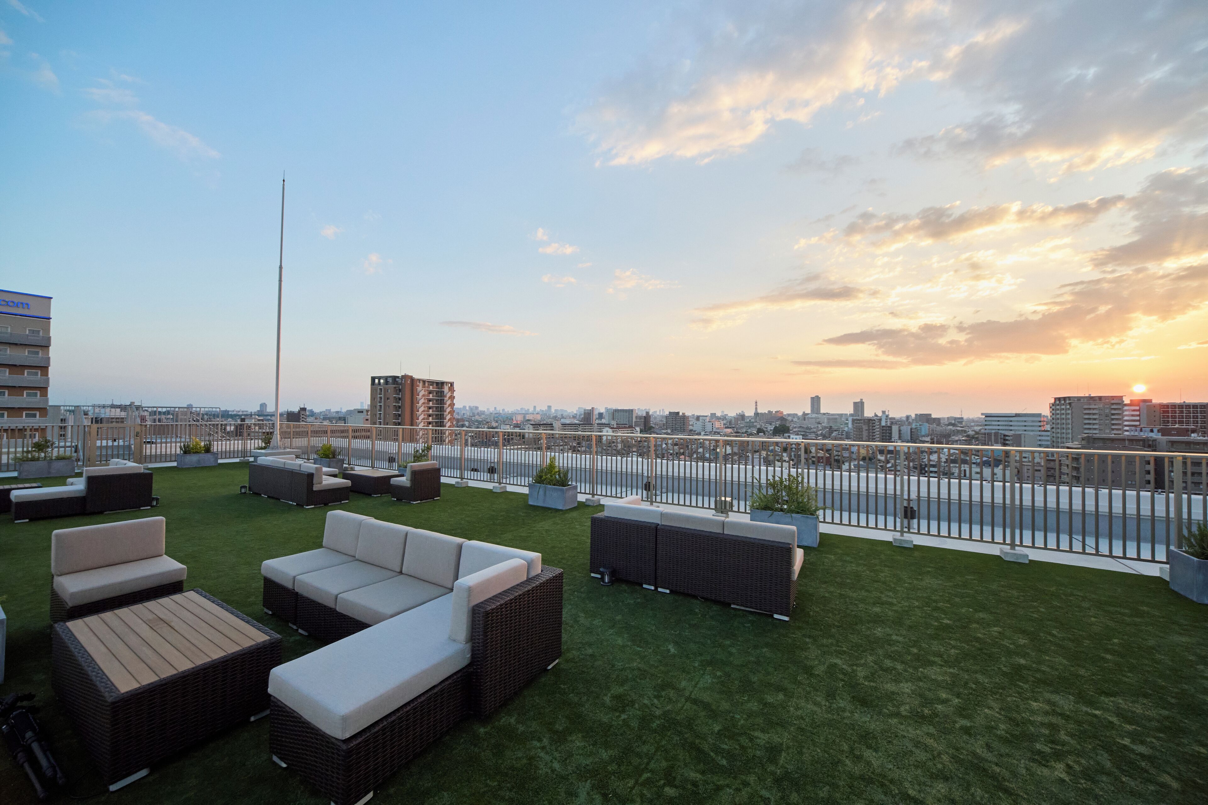 A rooftop terrace with outdoor seating and a city view at sunset.