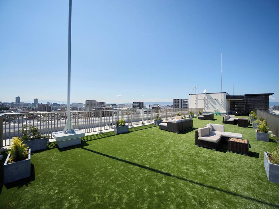 A rooftop terrace with artificial grass, outdoor seating, and city views.