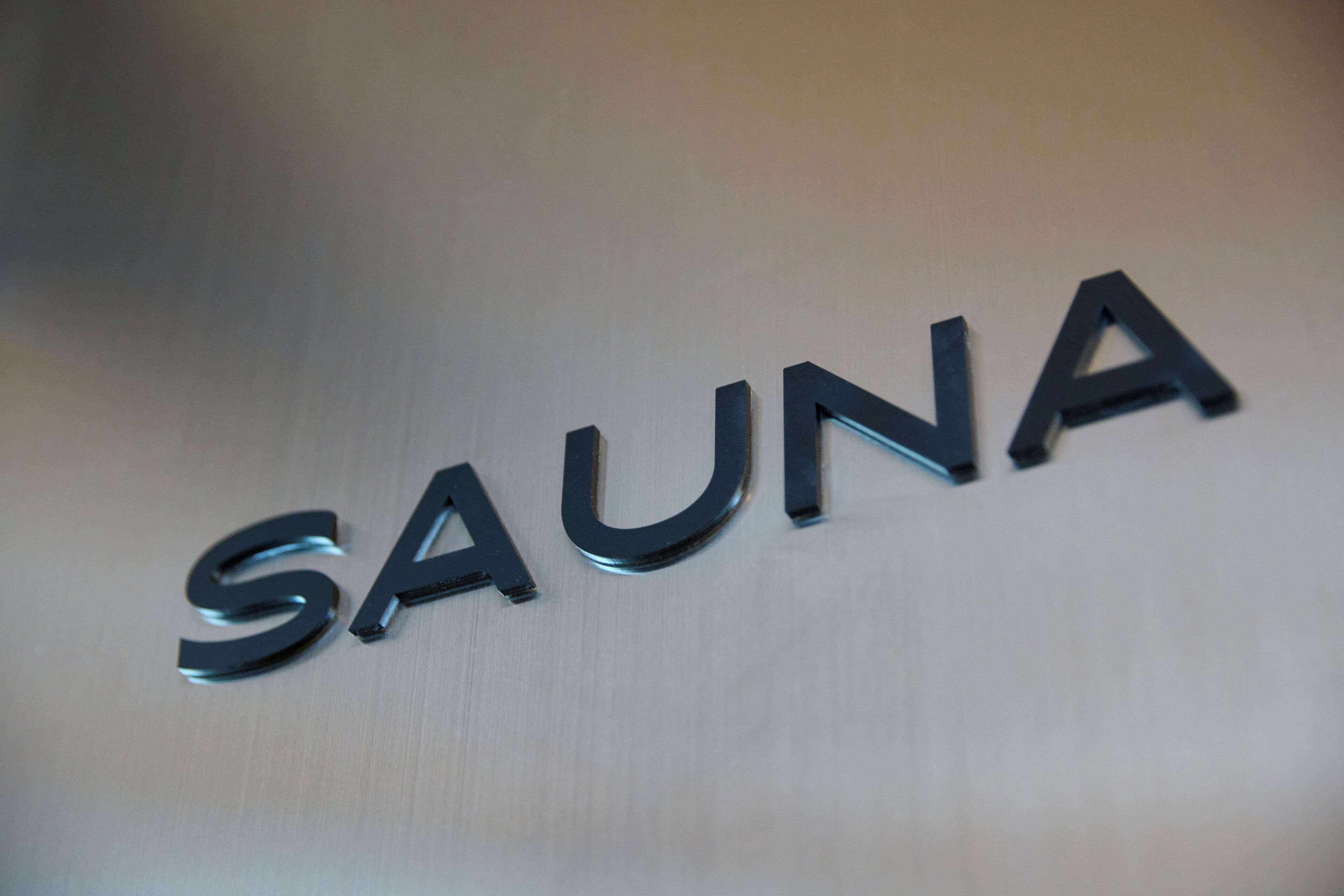 A metallic sign with the word "SAUNA" in capital letters.