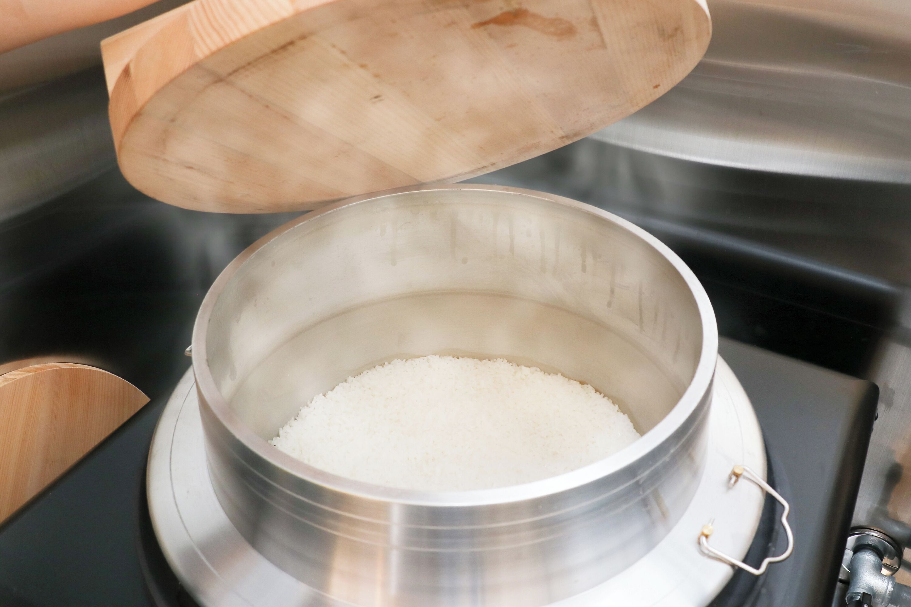 A stainless steel pot with a wooden lid on a stove.
