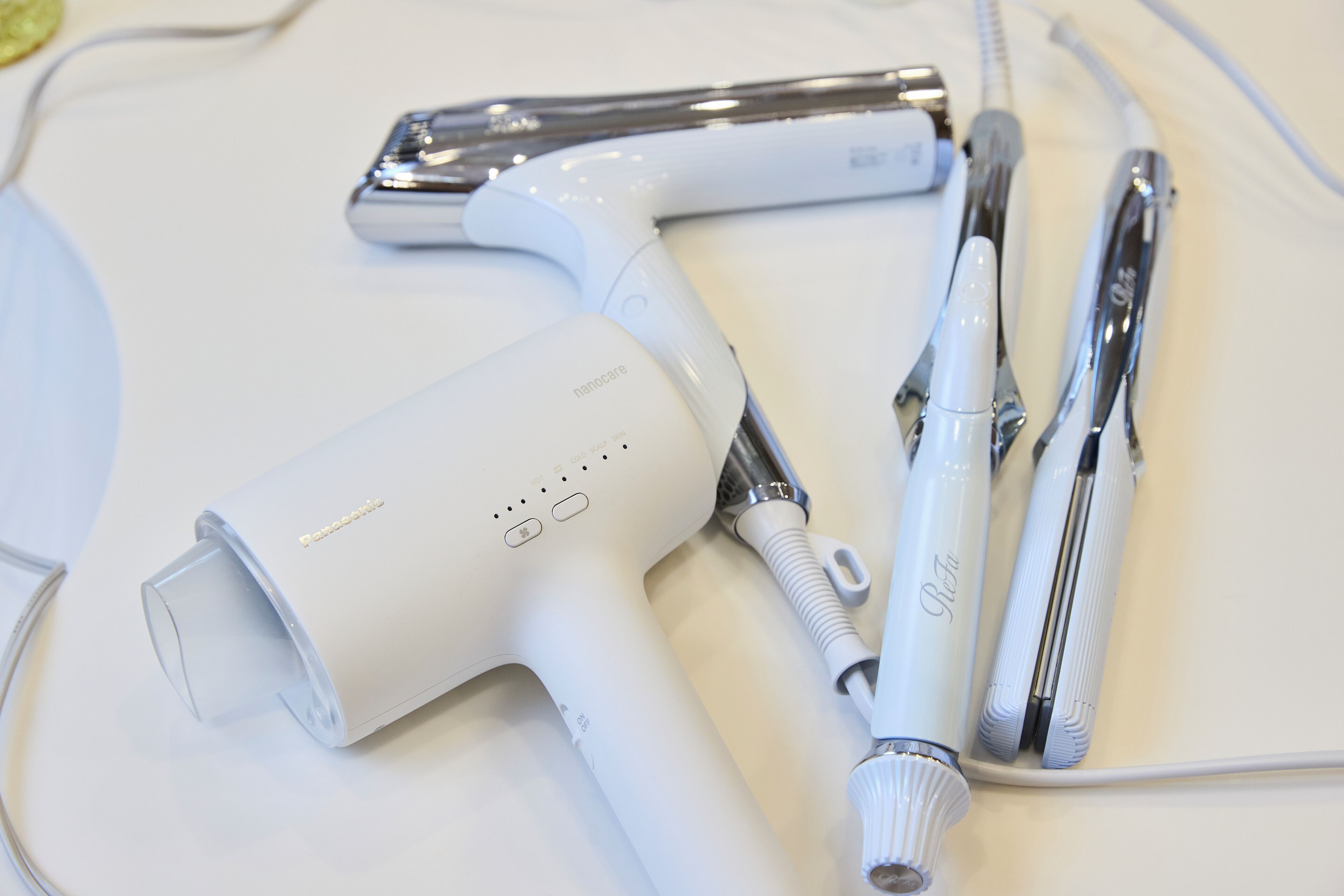 A hairdryer, a comb, and a pair of scissors on a white surface.