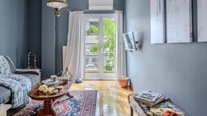 Une pièce comprenant un canapé, une table basse, un tapis à motifs, une lampe et une vue sur l’extérieur, visible à travers une porte vitrée.