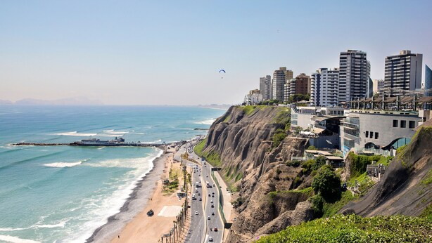 A coastal cityscape with a prominent cliff overlooking the beach, a busy road, and modern buildings. - Elegante Loft en Barranco (Lima)